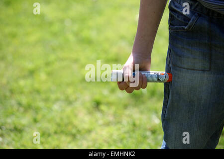 Ein Junge mit einem Epipen an seinem Oberschenkel zeigen was tun bei einem anaphylaktischen Schock Stockfoto