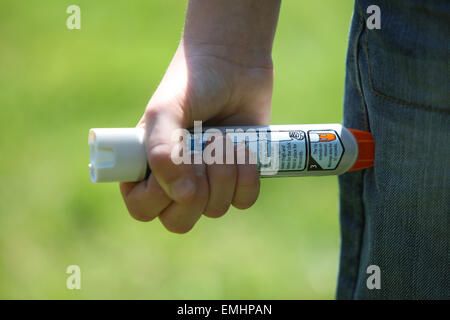 Ein Junge mit einem Epipen an seinem Oberschenkel zeigen was tun bei einem anaphylaktischen Schock Stockfoto