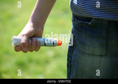 Ein Junge mit einem Epipen an seinem Oberschenkel zeigen was tun bei einem anaphylaktischen Schock Stockfoto