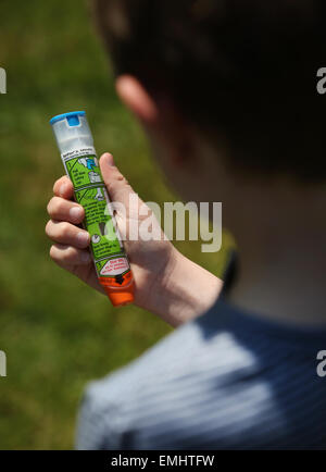 Ein Junge mit einem Epipen an seinem Oberschenkel zeigen was tun bei einem anaphylaktischen Schock Stockfoto