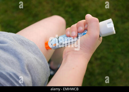 Ein Junge mit einem Epipen an seinem Oberschenkel zeigen was tun bei einem anaphylaktischen Schock Stockfoto