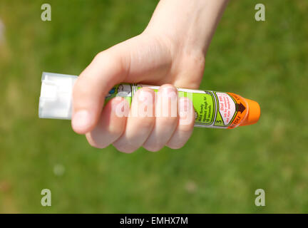 Ein Junge mit einem Epipen an seinem Oberschenkel zeigen was tun bei einem anaphylaktischen Schock Stockfoto