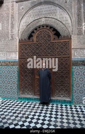 Al Attarine Madrasa, Fes, Marokko...  Reiseleiter vor reich verzierten Zeder Tür. Stockfoto