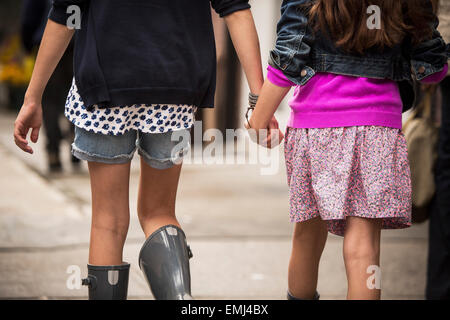 Zwei junge Mädchen Hand in Hand während des Gehens auf Gehsteig, close-up-Rückansicht Stockfoto