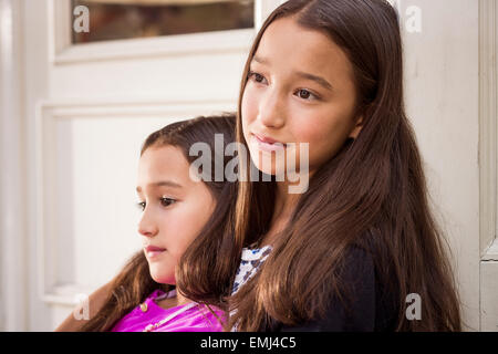 Porträt von zwei jungen Mädchen mit jüngeren Mädchen lehnte sich gegen ältere Mädchen, close-up Stockfoto