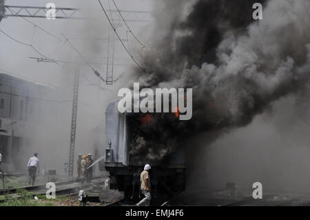 Neu-Delhi, Indien. 21. April 2015. Eine indische Feuerwehrmann sprüht Wasser um ein Feuer gefangen in den Trainern Sealdah Rajdhani Zuges in Neu-Delhi, Indien, 21. April 2015 zu begießen. Sechs Drehgestelle von einem Personenzug am Bahnhof New Delhi hier am Dienstag Feuer gefangen ohne jeden Schaden/Unfall, teilte die Polizei mit. © Partha Sarkar/Xinhua/Alamy Live-Nachrichten Stockfoto