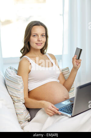 Schwangere Frau mit Laptop und Kreditkarte zu Hause Stockfoto