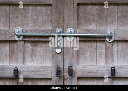 Eine alte Holztür mit rostigen alten Schleusen und neuere Silber sperren Stockfoto