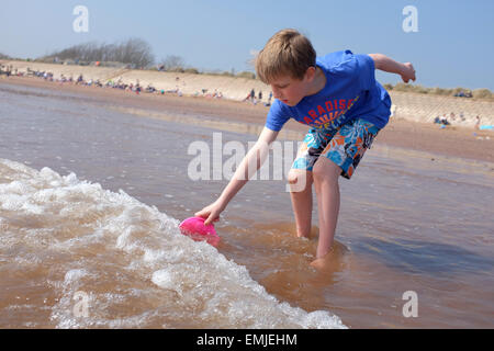 Ein Junge sammeln Wasser in einem Eimer an einem UK-Strand Stockfoto