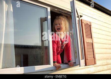 Ein junges Mädchen in ihrem Pyjama blickt aus dem Fenster einer Karawane zu Beginn eines neuen Tages Stockfoto