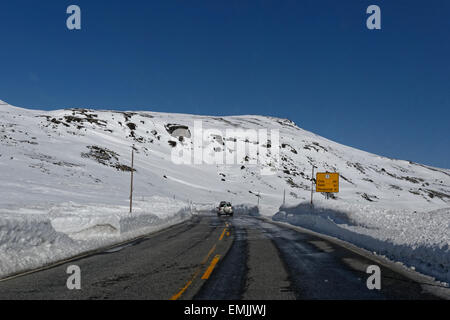 Auto Straßenfahrt Eastbound E7 über Hardangervidda, Norwegen, mit hoher Schneewände rund um die Straße. Stockfoto