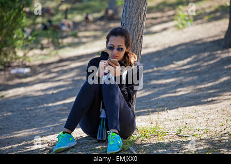 Frau SMS in einem Park, Novato, Marin County, Kalifornien, USA Stockfoto
