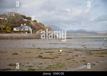 Ein Blick über Borth y Gest Hafen bei Ebbe mit Häusern auf einer felsigen Halbinsel und Snowdonia und Afon Dwyryd im Hintergrund Stockfoto