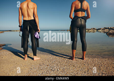 Verkürzten Blick auf Athleten stehen am Strand ein Rennen vorbereiten. Mann und Frau trägt einen Neoprenanzug Triathlon vorbereiten. Stockfoto
