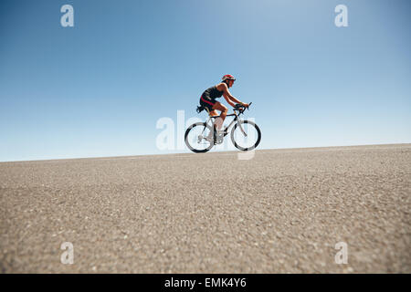 Weibliche Radfahrer auf einer Land-Straße-Training für Triathlon. Junge Frau Reiten Fahrrad bergauf. Stockfoto