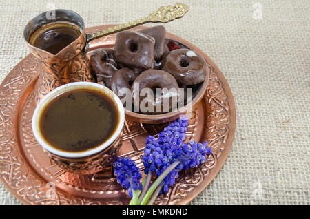 Türkischer Kaffee mit Keksen und Blumen in Kupfer Tassen auf einem Teller Stockfoto