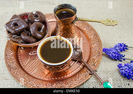 Türkischer Kaffee mit Keksen und Blumen in Kupfer Tassen auf einem Teller Stockfoto