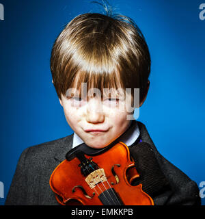 Junge rothaarige Vorschüler mit Violine, isoliert auf blau, Musikkonzept Stockfoto