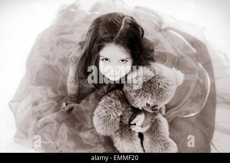 Niedliche kleine Mädchen gekleidet wie Prinzessin mit ihrem Freund Teddy-Bär Spielzeug Stockfoto