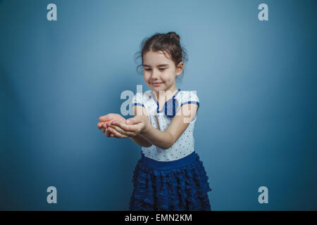 ein Mädchen von sieben europäischen Aussehen Brünette lächelnd Holding Objekt auf grauem Hintergrund, Glück Stockfoto