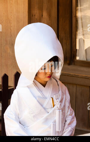 Japan, Nara, Tamukeyama Schrein. Japanische Braut sitzen im traditionellen shiromuku weissen Kimono und Cape Art Hut auf dem Kopf. Stockfoto