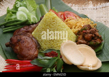 Ein indonesisches festliches Gericht von gelbem Reis mit Fleisch und Gemüse Beilagen. Stockfoto