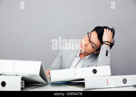 Müde asiatischen Geschäftsmann schlafen am Tisch mit Ordnern im Büro Stockfoto