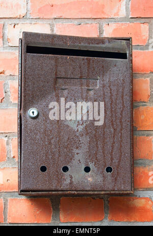 Eine alte und rostige Briefkasten vor einem roten brickwall Stockfoto