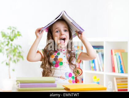 lächelndes Kind mit einem Buch über den Kopf in der Grundschule Stockfoto