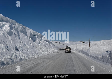 Auto Straßenfahrt Eastbound E7 über Hardangervidda, Norwegen, mit hoher Schneewände rund um die Straße. Stockfoto