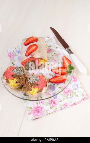 Erdbeer-Mohnkuchen mit weißer Schokolade Glasur auf Glasplatte zum Muttertag. Nächste Messer und Scheiben von frischem strawberri Stockfoto