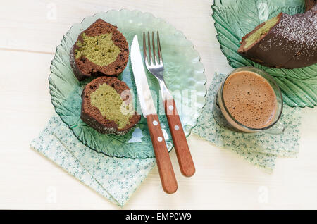 Zwei Scheiben Kuchen und eine Tasse schwarzen Kaffee auf weißem Hintergrund aus Holz. Draufsicht. Backen mit Tee Matcha. Aus Serie Coff Stockfoto