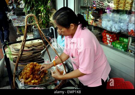 Bangkok, Thailand: Thai Frau verkaufen gebratene Bananen aus ihrem kleinen Warenkorb auf belebten Thanon Chakrabongse Stockfoto