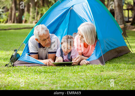 Großeltern mit Enkelin mit Digital-Tablette am Campingplatz Stockfoto