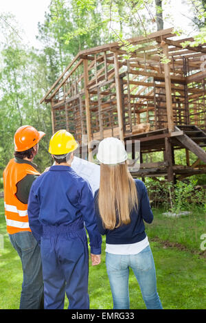 Architekten mit Blueprint Prüfung unvollständig Holzhütte Stockfoto