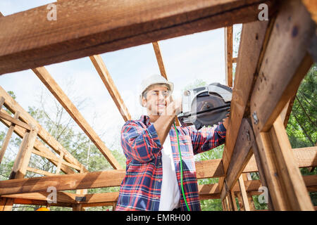 Bauarbeiter mit elektrischen sah auf Holzrahmen am Standort Stockfoto