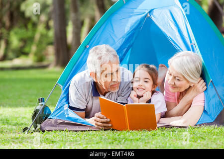 Großeltern mit Enkelin Lesebuch im Zelt Stockfoto