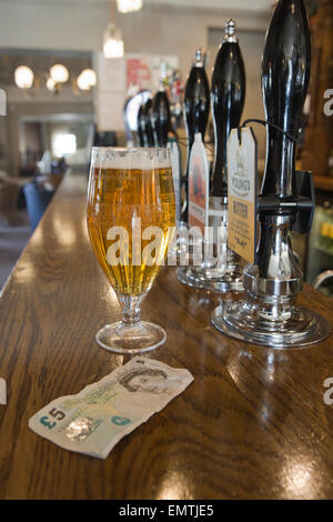 Ein Pint Lager und eine Anmerkung £5 auf eine Bar in einem Pub. Stockfoto