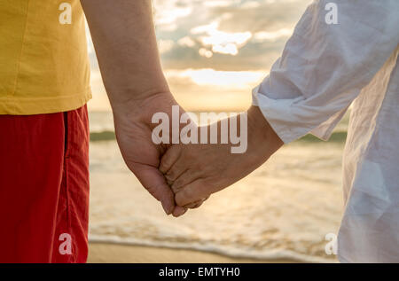 Ältere Mann und Frau, die Hand in Hand von einander am Strand Stockfoto
