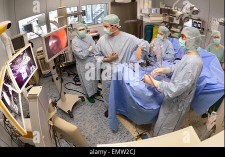 Attendings Mathias Hofer (vorne R) und Dirk Lindner (Front L) führen eine Operation an einem Patienten mit einem Hirntumor in einem OP-Saal der Leipziger Universitätsklinik Abteilung für Neurochirurgie in Leipzig, Deutschland, 22. April 2015. Die neueste Generation der Hightech-OP-Systeme ermöglichen Ärzten zu manövrieren und zu betreiben mit einer Genauigkeit von bis zu einem Millimeter während Operationen an Kopf und Wirbelsäule. Während des Eingriffs können Ärzte auch Zugriff auf das Bildarchiv der Radiologie und live-Aufnahmen von Ultraschall- und endoskopische Geräte als Referenz verwenden. Foto: Waltraud Grubitzsch/dpa Stockfoto