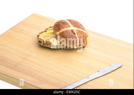 Hot Cross Bun mit Messer auf einem Holzbrett. Stockfoto