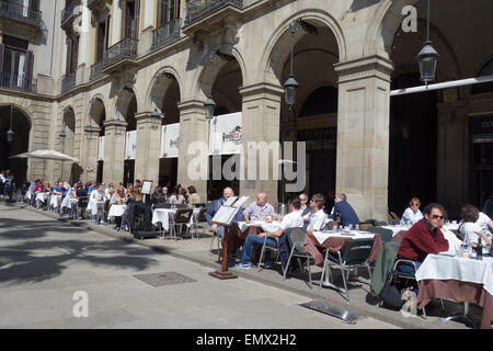 Leute sitzen in Straßencafés Restaurants im Sonnenschein in Plaza Real, Barcelona, Katalonien, Spanien Stockfoto