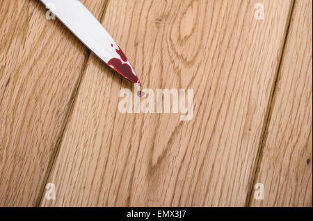 Blutverschmierte Messer auf einem Holzfußboden. Stockfoto