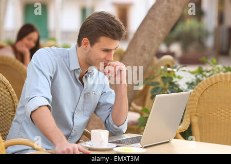 Selbstständiger Mann konzentriert Weile arbeitet mit einem Laptop in einem Restaurantterrasse Stockfoto