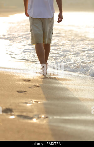 Hintergrundbeleuchtung ein Mann Beine am Strand Spuren Stockfoto