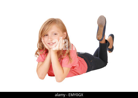 Ein blondes Mädchen in einem rosa Pullover auf dem Boden auf dem Bauch liegend lächelnd, isoliert auf weißem Hintergrund. Stockfoto