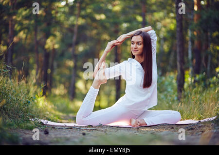 Flexible Frau dehnen ihre Beine und Arme im park Stockfoto