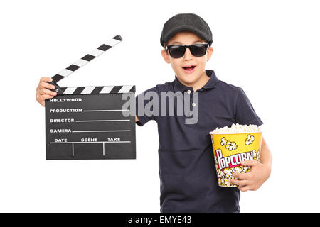 Kleines Kind mit einer Mütze und Sonnenbrille hält eine Schachtel mit Popcorn und einem Filmklappe isoliert auf weißem Hintergrund Stockfoto