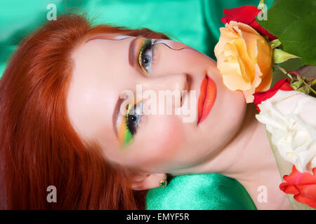 Porträt von schönen Rothaarigen Mädchen mit Blumen und hellen Make-up Stockfoto