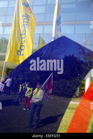 Bonn, Deutschland. 24. April 2015. Mitarbeiter der Postbank spiegeln sich im Logo der Bank auf Glas, wie sie token Streiks vor der Postbank in Bonn, Deutschland, 24. April 2015 teilnehmen. Eine Sitzung des Aufsichtsrats entscheidet über die zukünftigen Strategien der das Finanzinstitut. Die Entsorgung der Postbank ist eine der Optionen sowie der Ausgliederung der gesamten Privat banking inklusive Postbank. Foto: Oliver Berg/Dpa/Alamy Live News Stockfoto